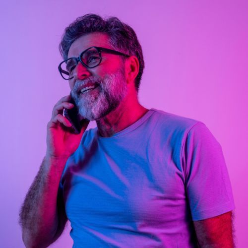 Man talking on a phone against a neon gradient background